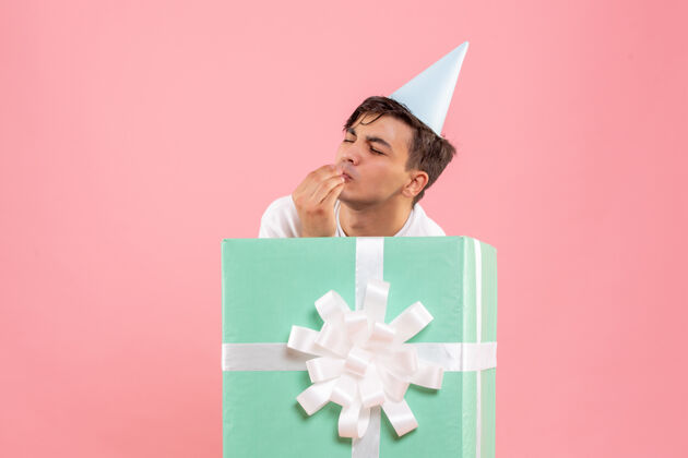 圣诞一个年轻人躲在粉红色的墙上礼物的正面视图礼品盒节日圣诞快乐