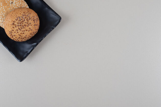 饼干把饼干捆在大理石背景的黑色盘子里甜点芝麻调味品