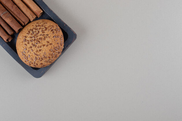 曲奇在大理石背景的小托盘上放上芝麻饼和一捆肉桂棒烘焙甜点调味品