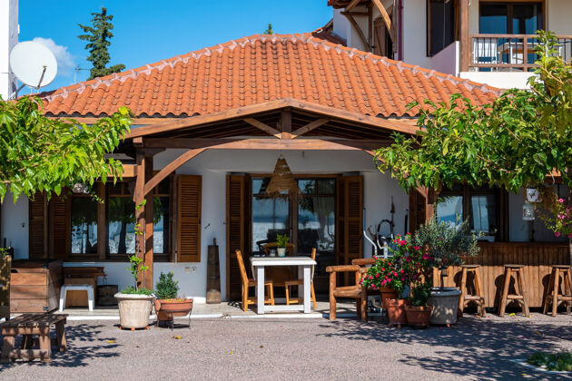 黄色前院和阳台的一家餐厅在民族风格与绿色植物 椅子和桌子在尼基蒂 希腊椅子典型花园