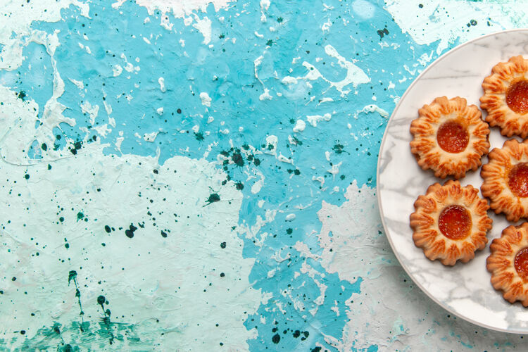 饼干俯瞰美味饼干圆形果酱形成的浅蓝色桌子上的盘子饼干糖甜饼干面团蛋糕烘烤里面浅蓝色蛋糕