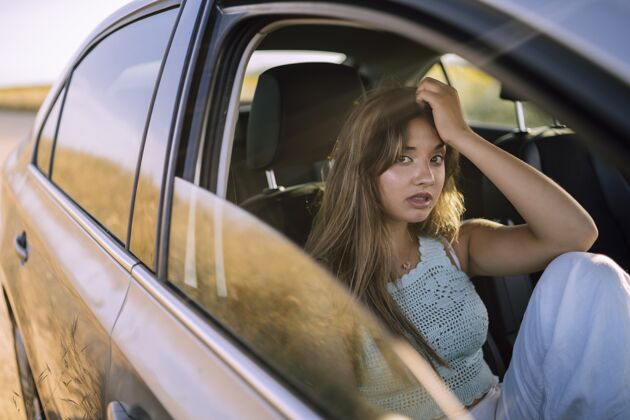 女性一个美丽的年轻白人女性在一个领域的汽车前排座位摆姿势的水平镜头运动车轮汽车