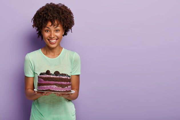 庆祝快乐的美国黑人妇女手持美味的蓝莓生日蛋糕 用美味的甜点招待客人高兴吃快乐