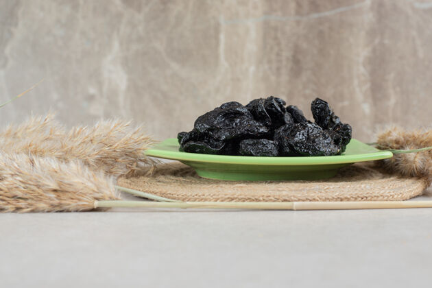 美味陶瓷盘子里的干黑李子甜水果产品