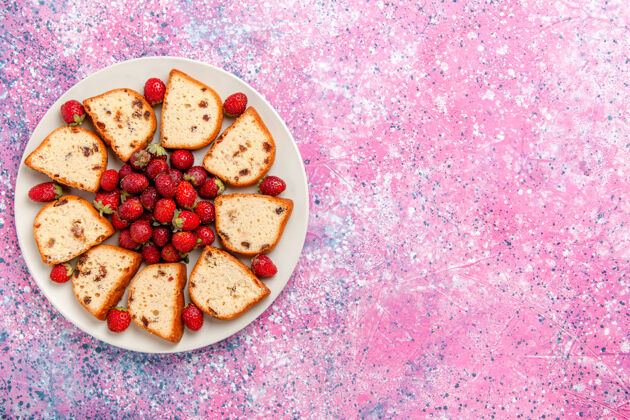 里面顶视图蛋糕片与葡萄干在盘子里与新鲜的红色草莓在粉红色的背景蛋糕烤甜饼干颜色派糖饼干可食用颜色饼干