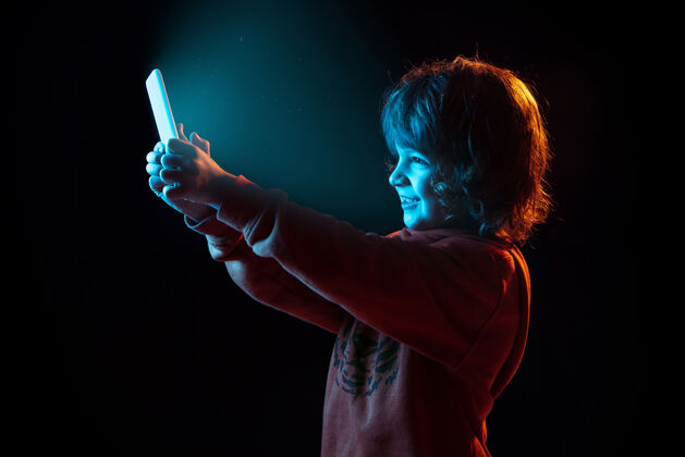 情感白种人男孩的肖像在霓虹灯下的黑暗工作室里被孤立表情互联网广告