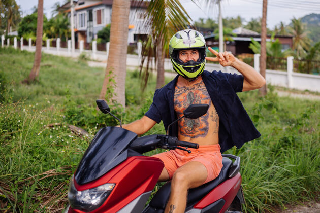 控制在热带丛林的田野上纹着红色摩托车的壮汉景观交通人