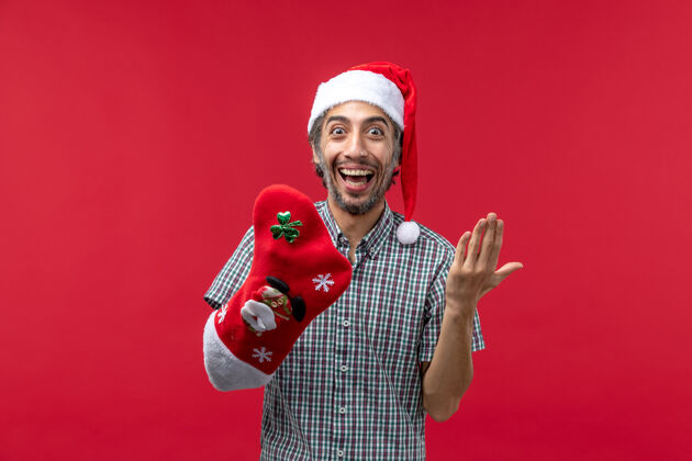 穿着红墙上穿着圣诞袜的年轻人的正视图男性袜子帽子