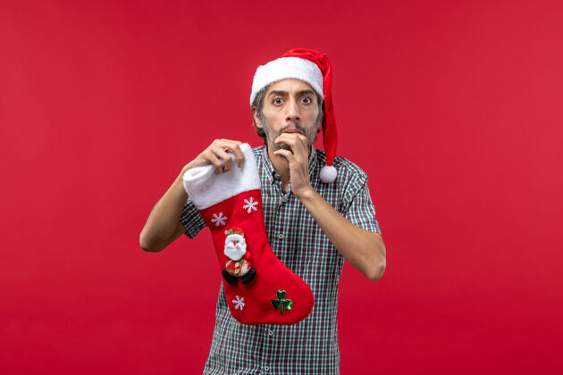 节日红墙上穿着圣诞袜的年轻人的正视图麦克风脸表情