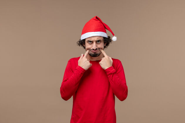 人正面图：棕色背景的年轻人带着悲伤的脸圣诞节情感假期圣诞节年轻脸