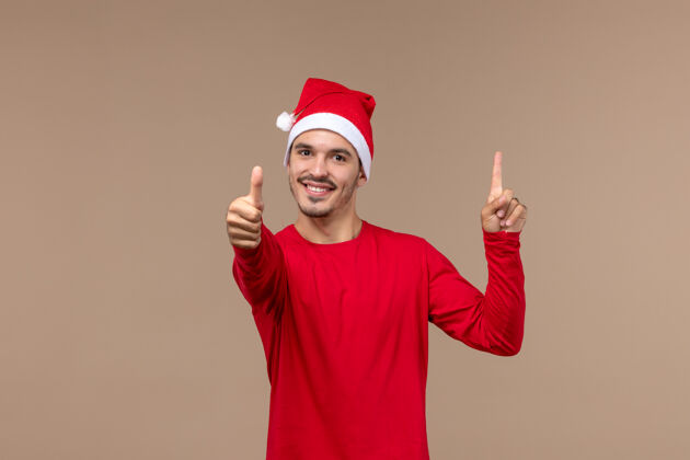 男性正面图棕色背景上微笑的年轻男性圣诞节情感假期年轻男性假日工作