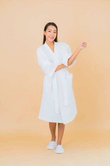 成人肖像美丽的亚洲年轻女子穿着米色的微笑浴袍保湿模特面霜