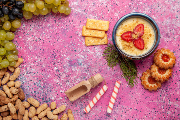 新鲜顶视图美味的奶油甜点与新鲜葡萄饼干饼干和花生上浅粉红色的办公桌甜点冰淇淋浆果奶油甜水果清淡葡萄花生