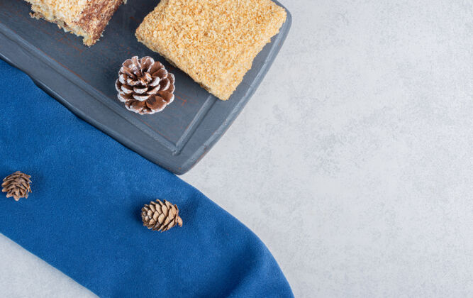 圆锥体在海军蓝板上的蛋糕片 大理石表面有松果糖蛋糕装饰的