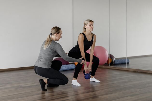 锻炼与私人教练一起做深蹲训练健康健身房客户