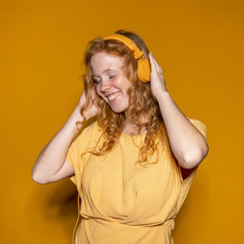 庆祝听音乐的红发女人美丽耳机欢快