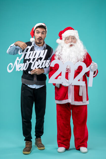 圣诞快乐圣诞老人的正面图 男主人在蓝色的墙上举着新年快乐和2021年的木板圣诞老人男性节日
