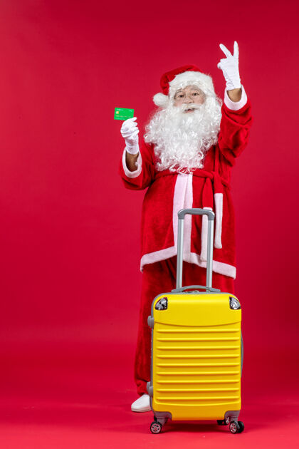 快乐红墙上挂着黄色袋子 手里拿着绿色银行卡的圣诞老人的正视图假日前面银行