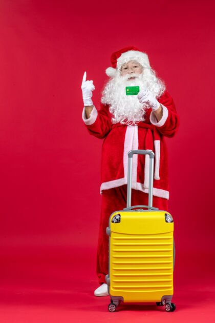 十二月红墙上挂着黄色袋子 手里拿着绿色银行卡的圣诞老人的正视图圣诞圣诞老人前面
