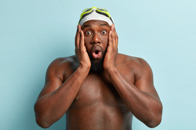 裸体专业游泳运动员用omg表情抚摸脸颊和面容 是一个活跃的运动员 皮肤黝黑 戴泳帽和护目镜 震惊了他的球队输掉比赛游泳困惑男子