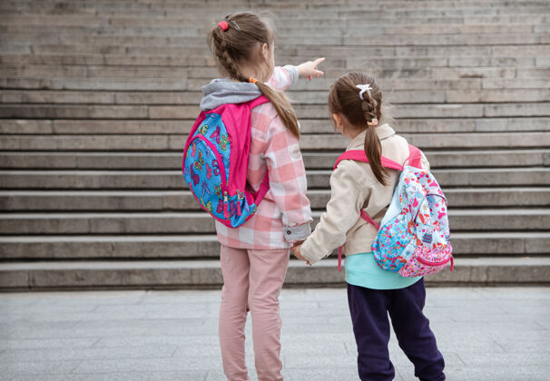 女生两个背着背包的小女孩手牵手一起上学童年的友谊背包一起友谊