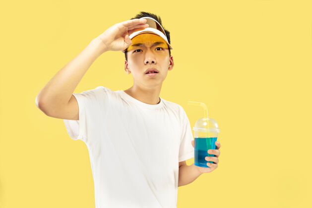 情感韩国年轻人的肖像穿白衬衫 戴黄帽子的男模喝鸡尾酒人类情感的概念 表达 夏天 假期 周末喝酒男海洋