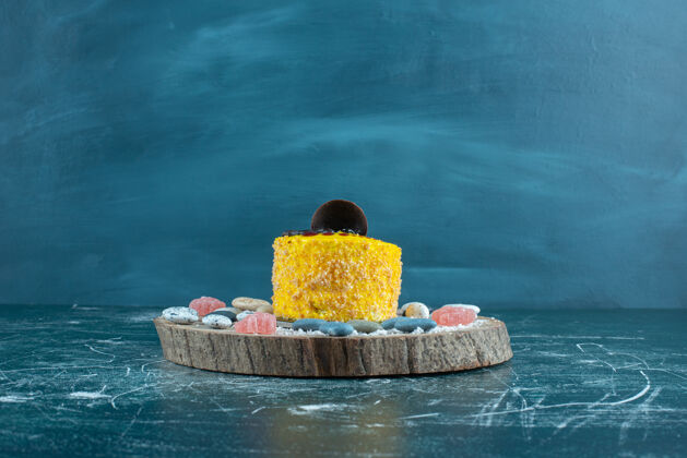配料黄色的蛋糕和糖果块放在蓝色的木板上岩石糖果巧克力