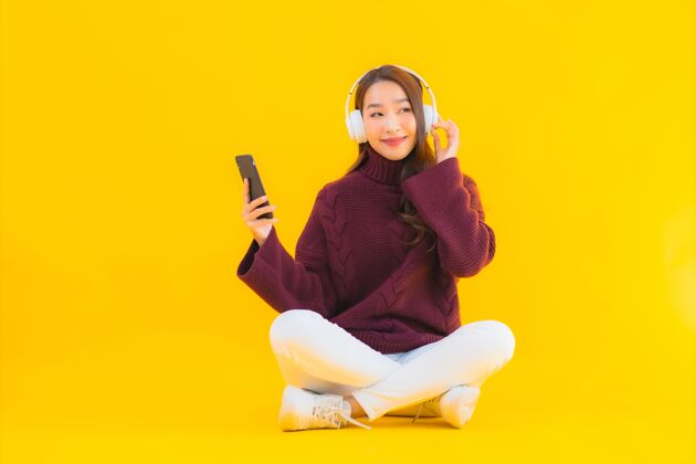 快乐肖像美女亚洲年轻女子用智能手机听音乐工作复制空间购买
