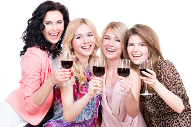 友谊年轻快乐的女人们尽情享受和喝红酒的画像-孤立于白色之上喝酒坐着大笑