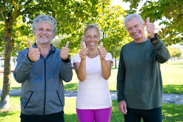 男人开朗的运动型成熟人士在公园晨练后站在一起 微笑着竖起大拇指退休或积极的生活方式概念喜欢肖像拇指向上