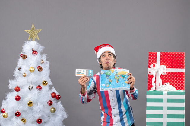 家伙前视图惊讶的男子与螺旋弹簧圣诞帽举行世界地图和旅行票长袜举行快乐