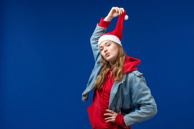 圣诞节前视图年轻女性 蓝色背景上戴着红色圣诞帽蓝色快乐成人