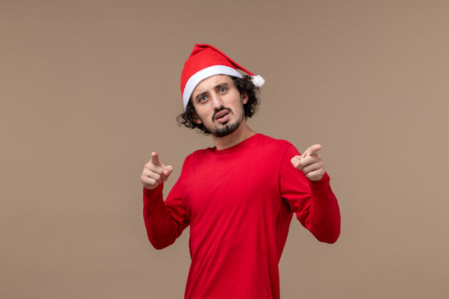 红色正面图：身着红色圣诞斗篷的年轻人在棕色背景下度过圣诞节男人帽子情感
