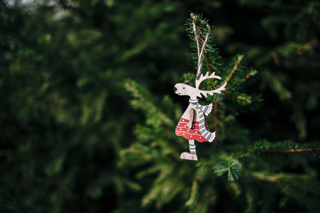 松特写一个可爱的木制鹿形圣诞饰品挂在松树上庆祝鹿形状