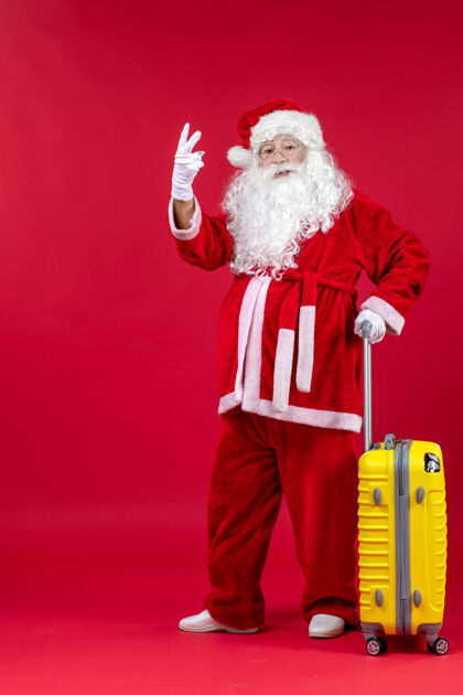 旅行红墙上准备旅行的黄包圣诞老人的正视图人快乐快乐