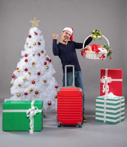 圣诞树圣诞树旁的圣诞老人戴着圣诞帽 手里拿着礼品篮 高兴极了高兴礼物圣诞帽