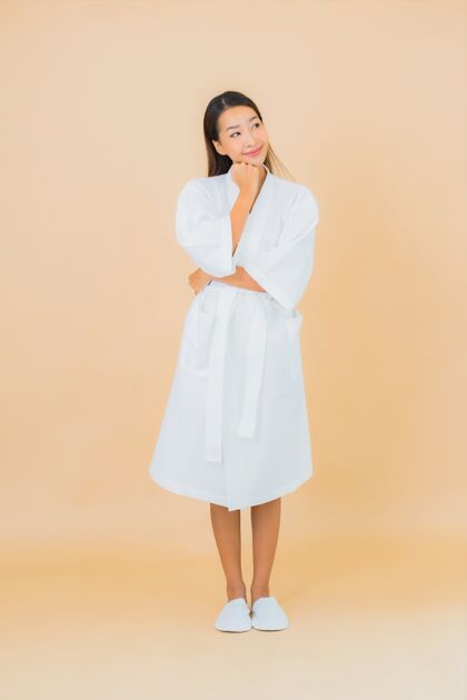 亚洲肖像美丽的亚洲年轻女子穿着米色的微笑浴袍保湿浴缸清洁
