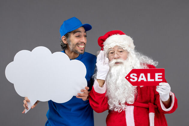 快乐圣诞老人的正面图 男信使手持白云招牌 在灰色墙上出售云人庆祝