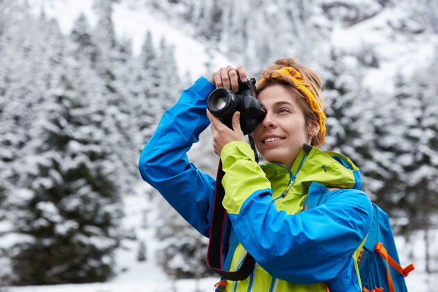 下雪美女在专业相机上拍照享受寒冷雪