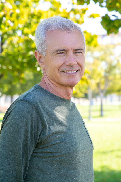 60多岁快乐积极的成熟男人穿着运动长袖衬衫 站在外面 微笑着中枪成熟的运动型人或积极的生活方式的概念草地中等袖子
