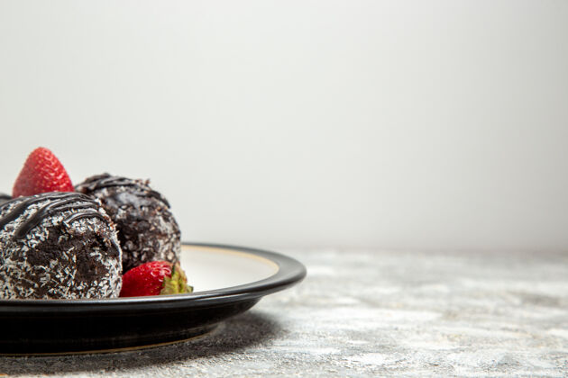 生的正面图美味的巧克力蛋糕配上新鲜的红草莓 表面呈浅白色巧克力糖饼干甜蛋糕烘烤淡白色甜点新鲜