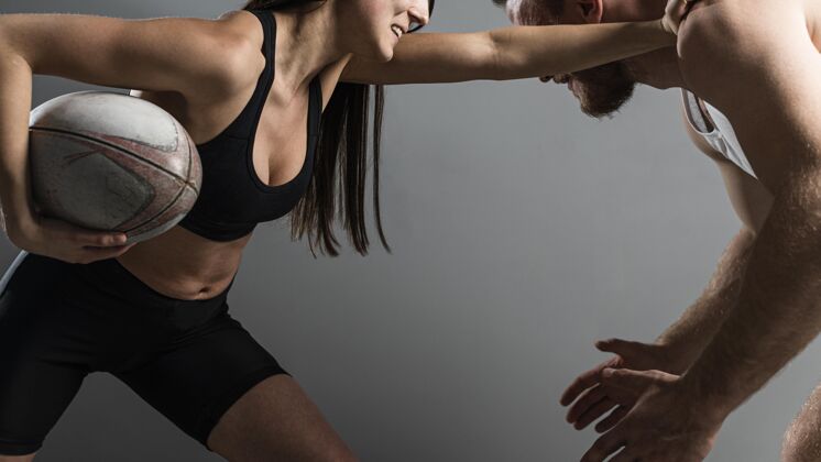 运动男女橄榄球运动员争夺球的侧视图完全接触比赛女子