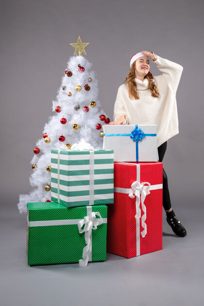 人年轻的女性在灰色的礼物圣诞树包圣诞