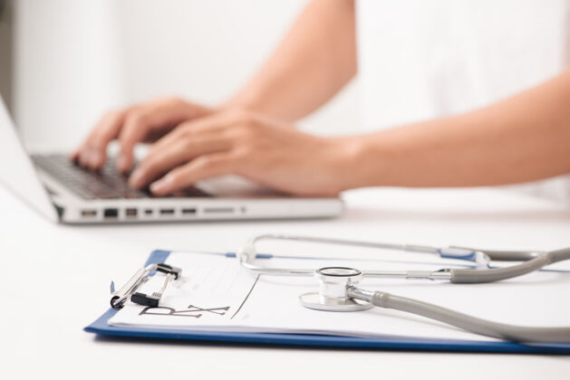文件一位女医生坐在医院的桌子旁用笔记本电脑打字的特写镜头医疗女人书写