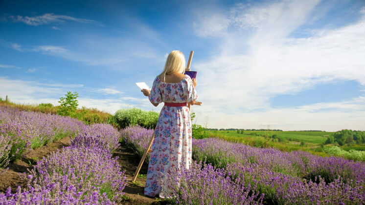 服饰美丽的年轻女子早上在薰衣草地上画画乡村绘画风景