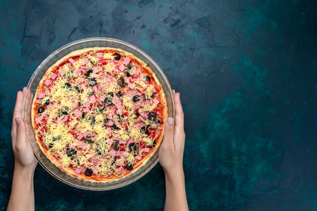 比萨饼顶视图美味奶酪比萨饼橄榄番茄酱香肠在浅蓝色背景的玻璃锅里快餐橄榄食物