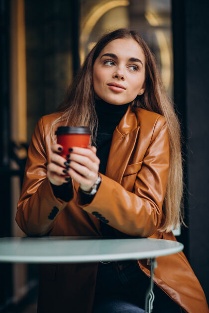 现代坐在咖啡馆外面喝咖啡的年轻女孩快乐露台好