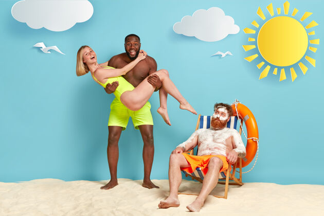沙滩一张快乐的黑皮肤男人手上抱着穿着泳装的女友的照片救生圈皮肤三