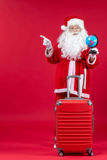 人们圣诞老人的前视图 包里装着小地球仪 准备在红墙上旅行假期前面圣诞快乐
