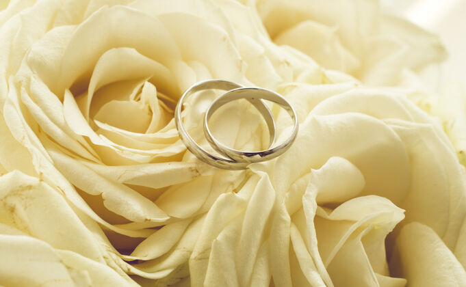 仪式婚礼的色调背景 戒指放在白玫瑰上花束音调订婚